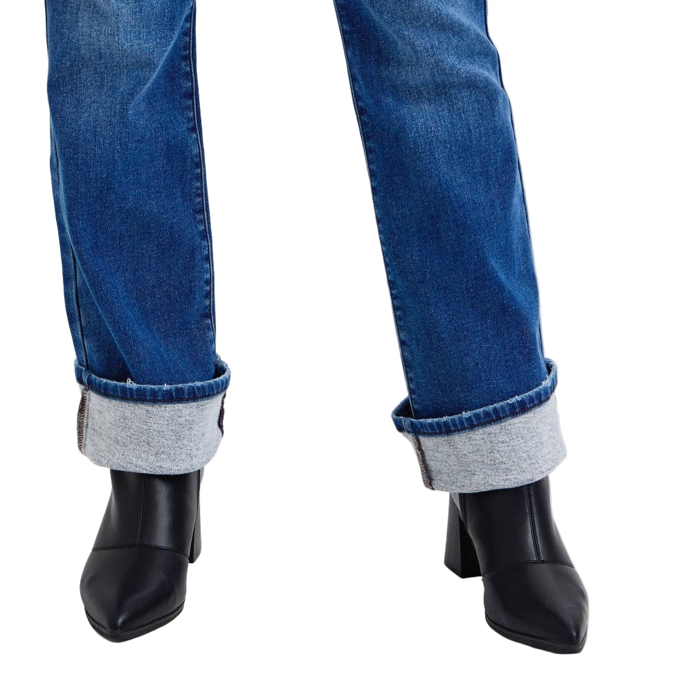 Blue jeans with rolled-up cuffs and black pointed-toe boots on a white background