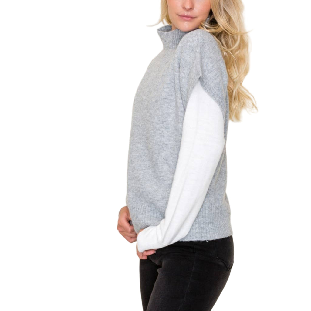 Woman wearing a gray and white sweater against a plain background