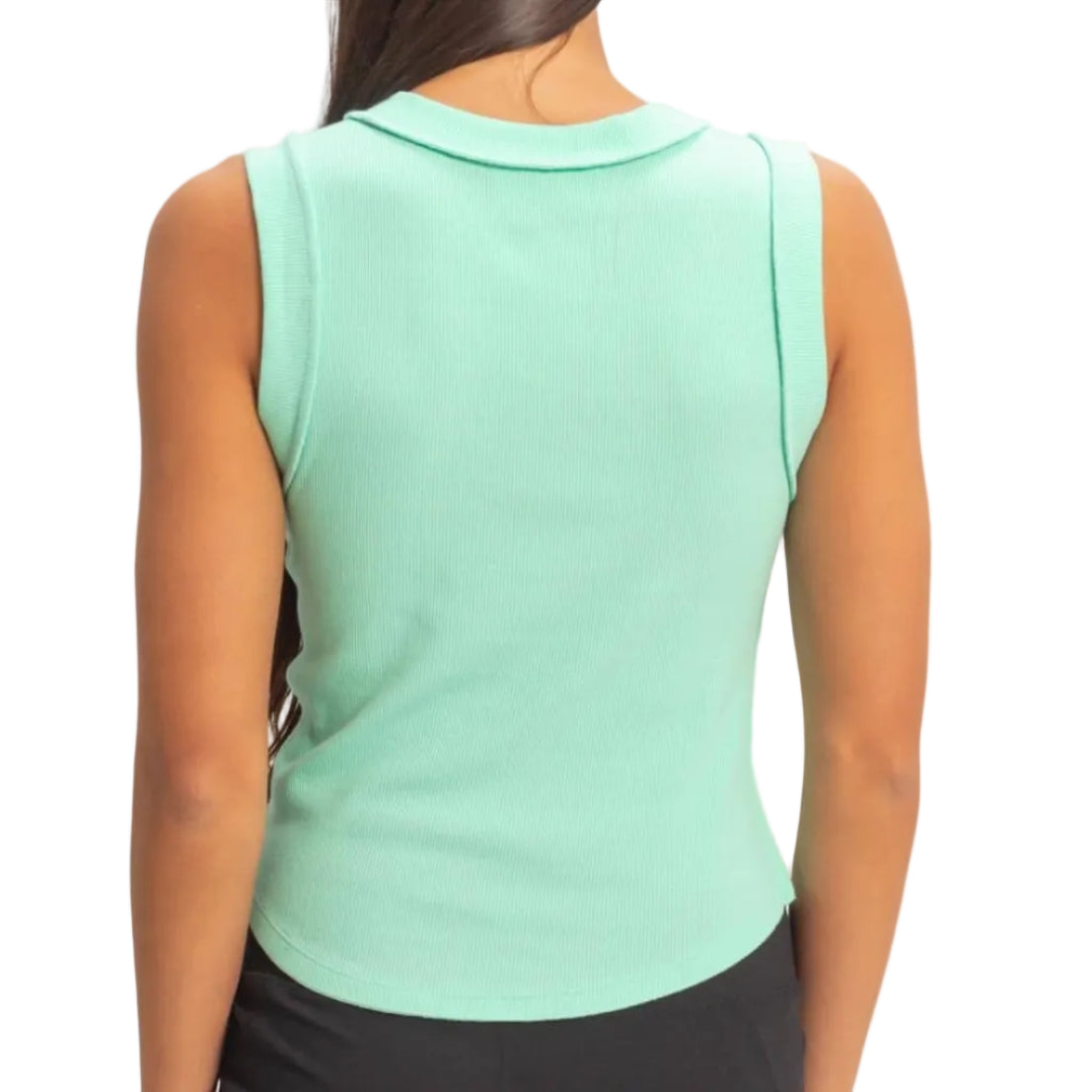 Woman wearing a light green sleeveless top and black shorts on a beige background