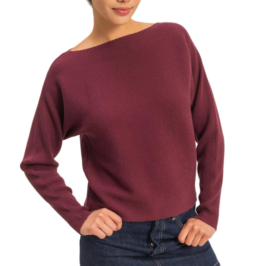 Woman wearing a burgundy sweater and denim skirt on a plain background