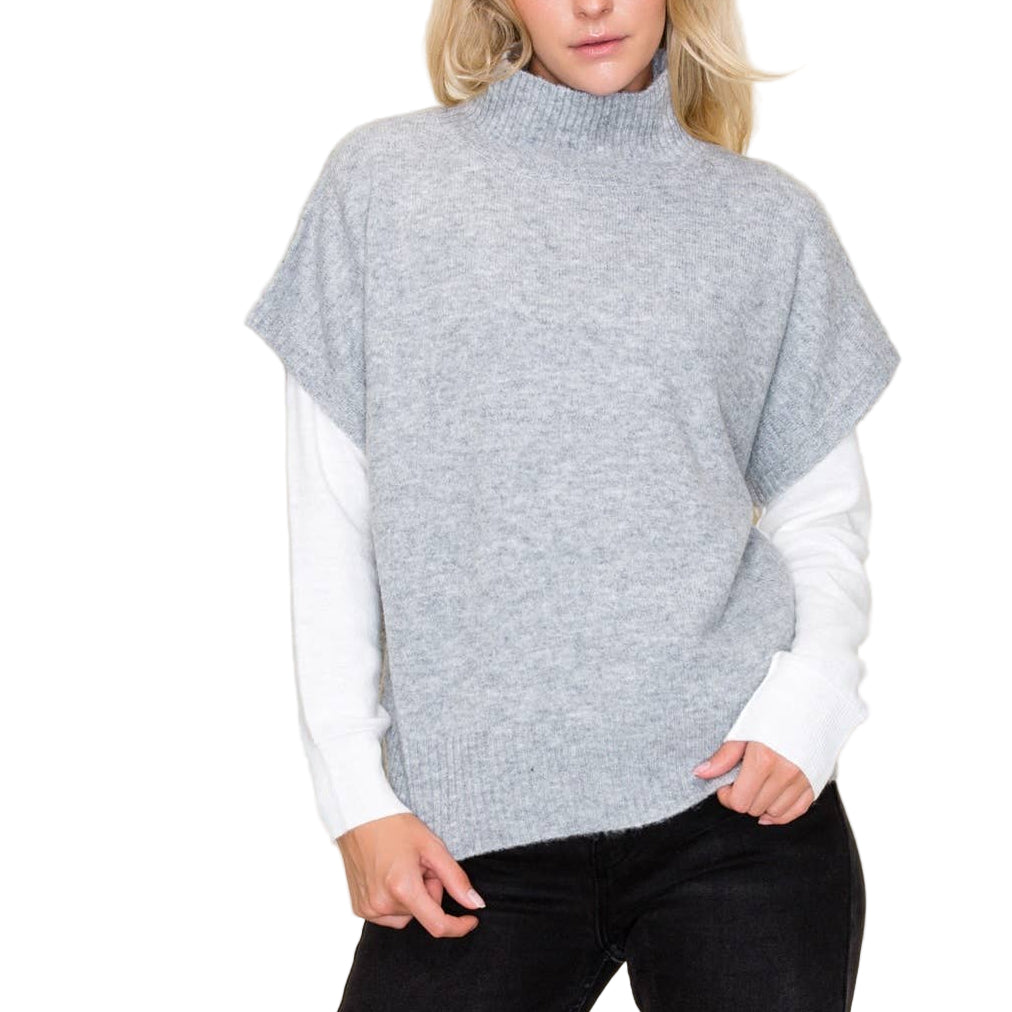 Woman wearing a gray poncho over a white shirt with a beige background