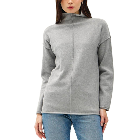 Woman wearing a gray zip-up sweater and blue jeans on a white background