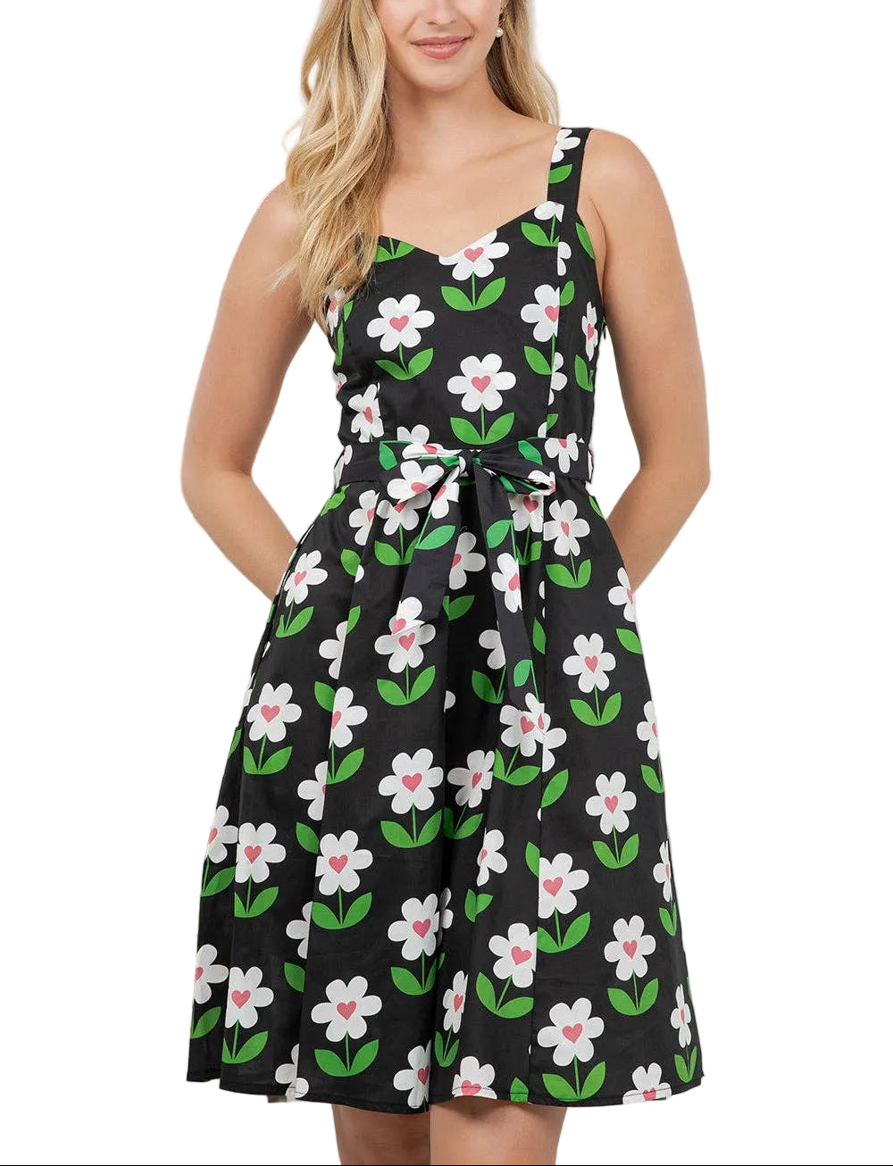 Woman wearing a black dress with floral pattern standing indoors.