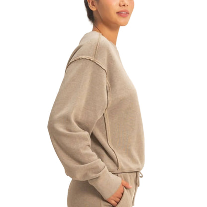Woman wearing a beige tracksuit against a plain background