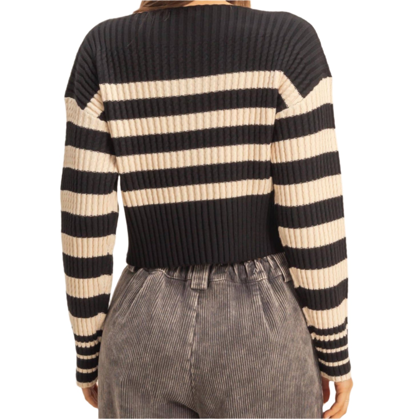 Person wearing a black and beige striped sweater with gray pants on a beige background