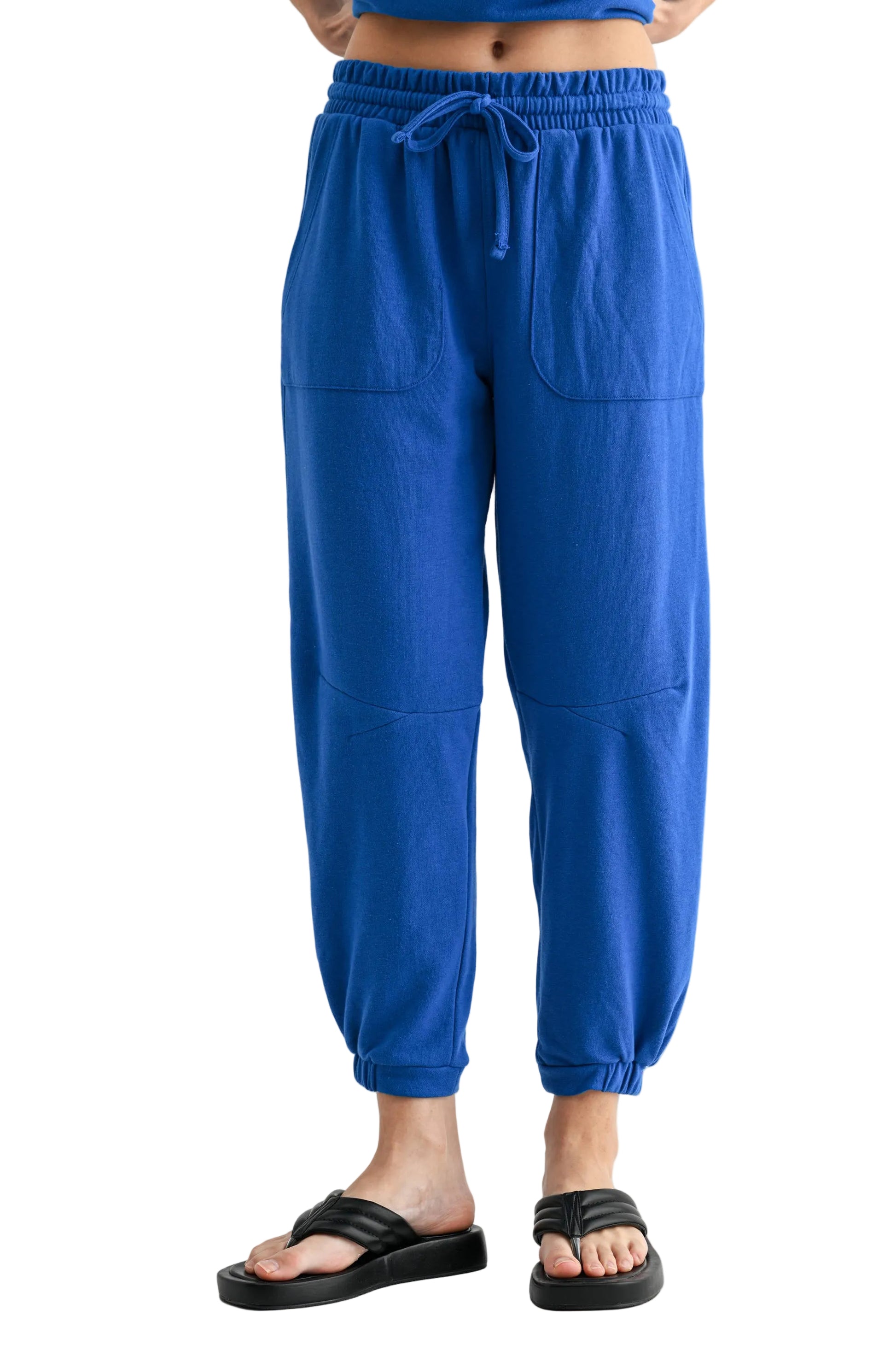 Blue jogger pants worn by a person on a white background