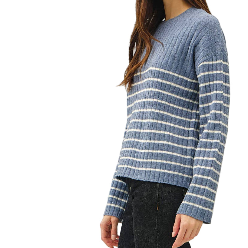 Woman wearing a blue striped sweater and black pants on a white background