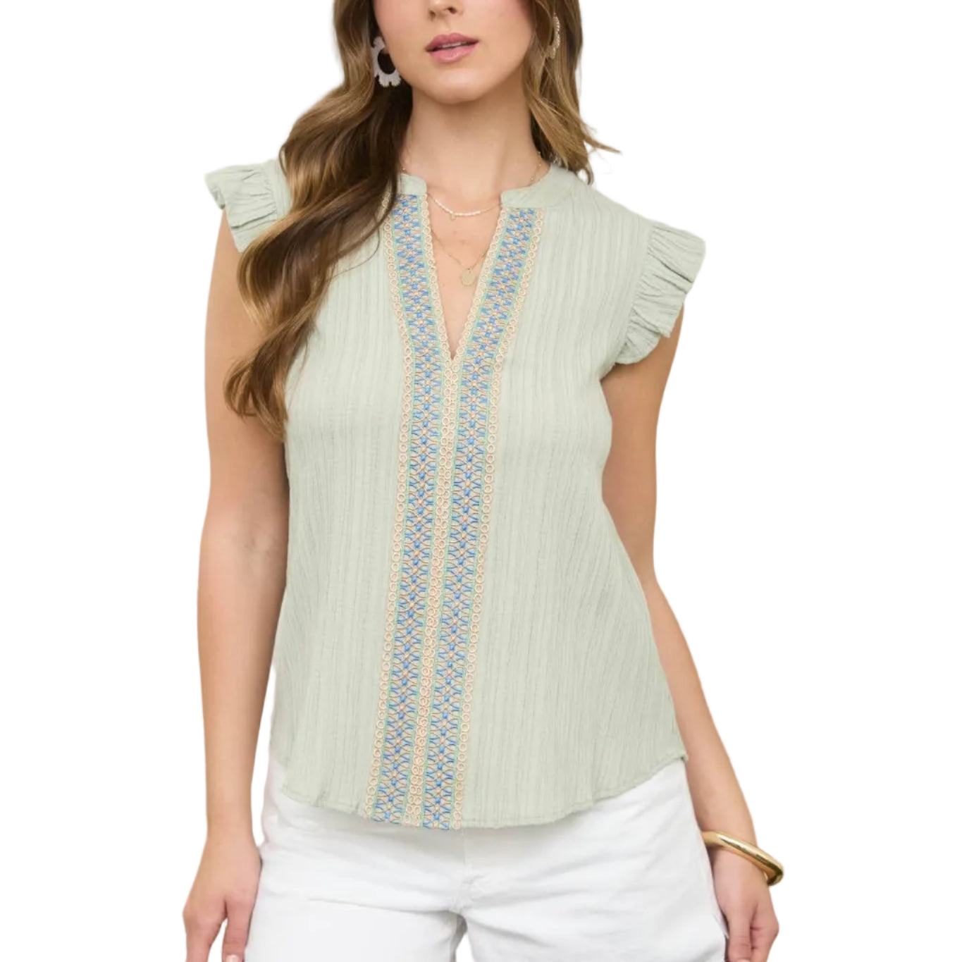 Woman wearing a light green blouse with lace details in an outdoor setting.