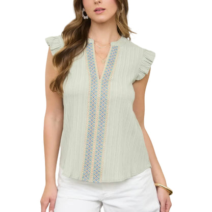 Woman wearing a light green blouse with lace details in an outdoor setting.