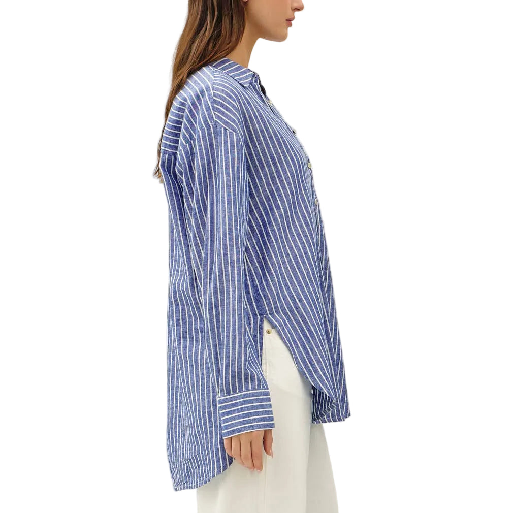 Woman wearing a blue and white striped shirt and white pants on a white background