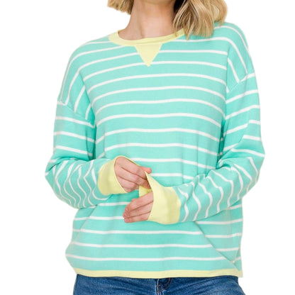 Woman wearing a green and white striped shirt with yellow accents on a plain background