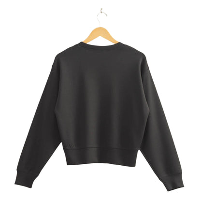 Black sweatshirt on a wooden hanger against a beige wall
