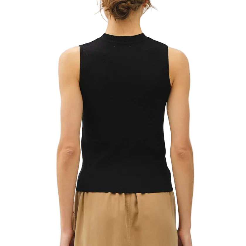 Woman wearing a black sleeveless top and beige skirt on a white background