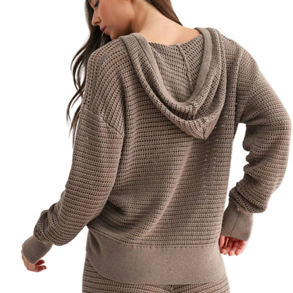 Woman wearing a brown knitted hoodie and pants on a light gray background