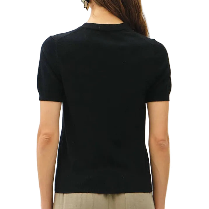 Person wearing a black top and beige pants on a white background