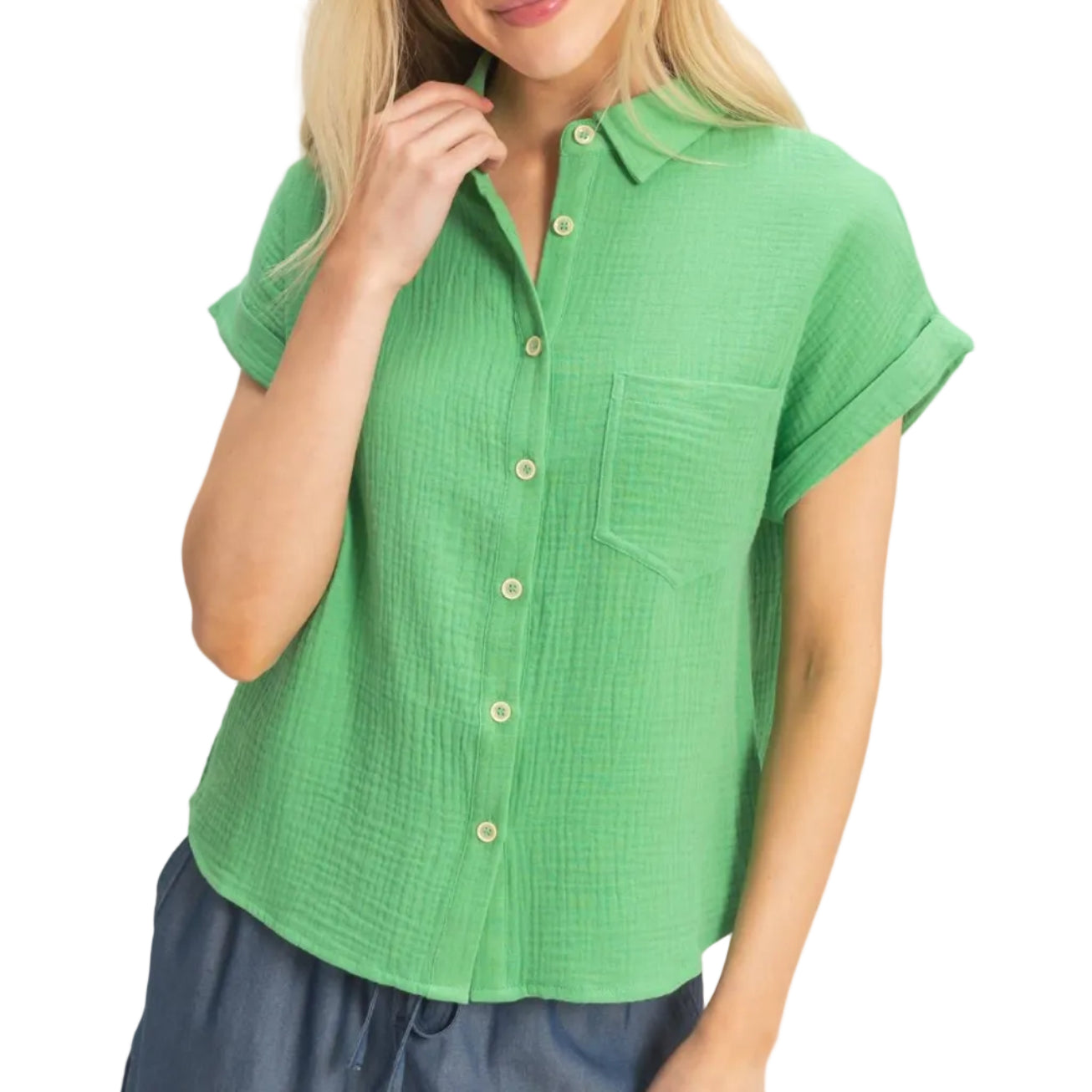 Woman wearing a green short-sleeve shirt and blue shorts on a plain background