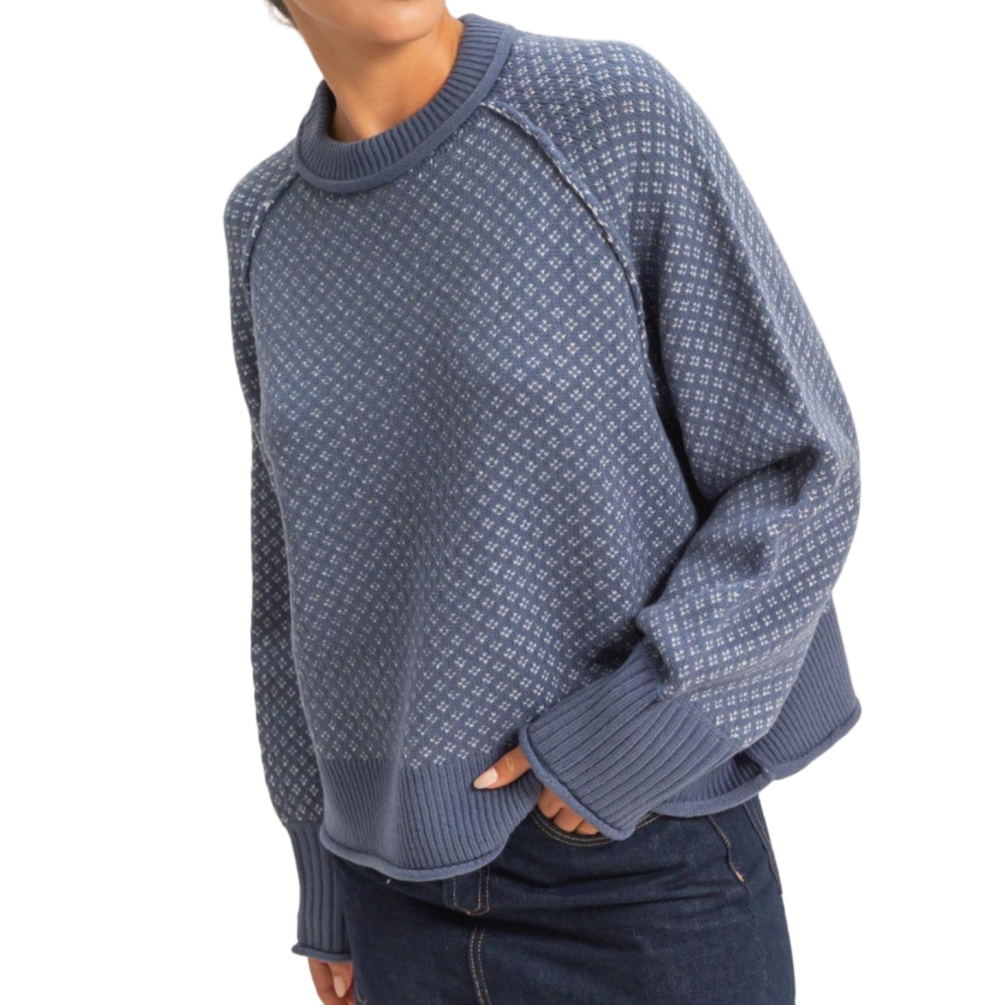 Woman wearing a blue patterned sweater and denim shorts on a beige background