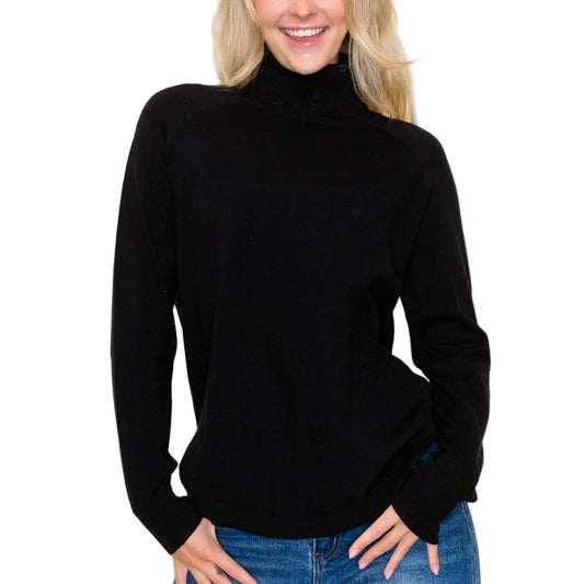 Woman wearing a black turtleneck sweater and blue jeans against a plain background