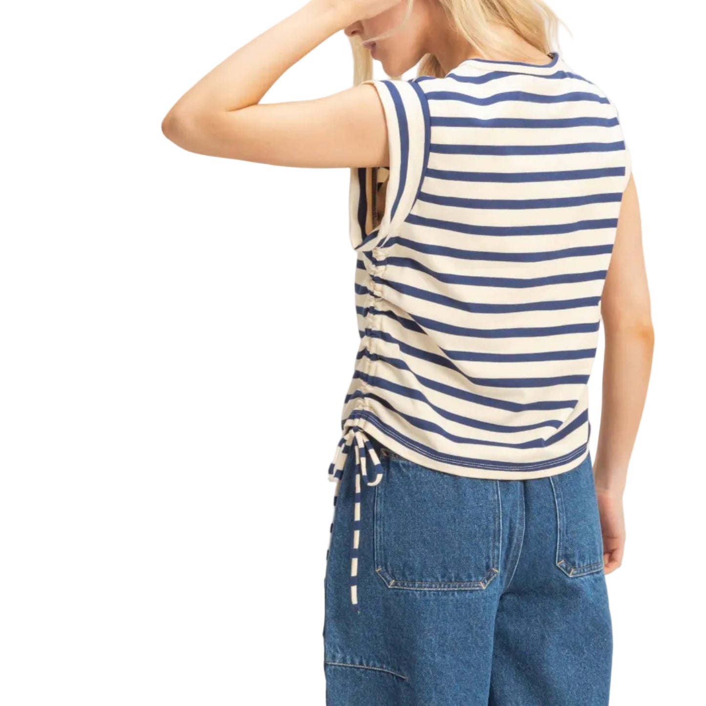 Woman wearing a blue and white striped sleeveless top with denim pants on a plain background