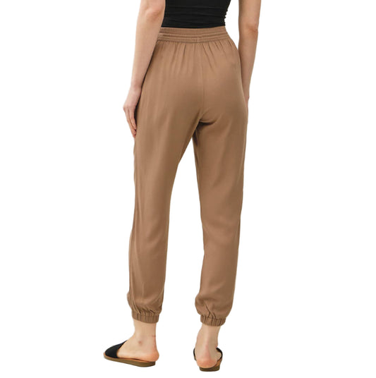 Woman wearing a black strapless top and beige pants against a white background