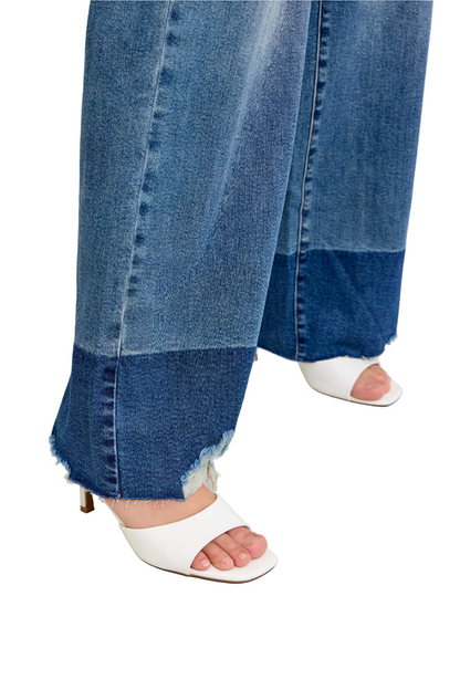 Blue jeans with raw hem and white sandals on a light gray background