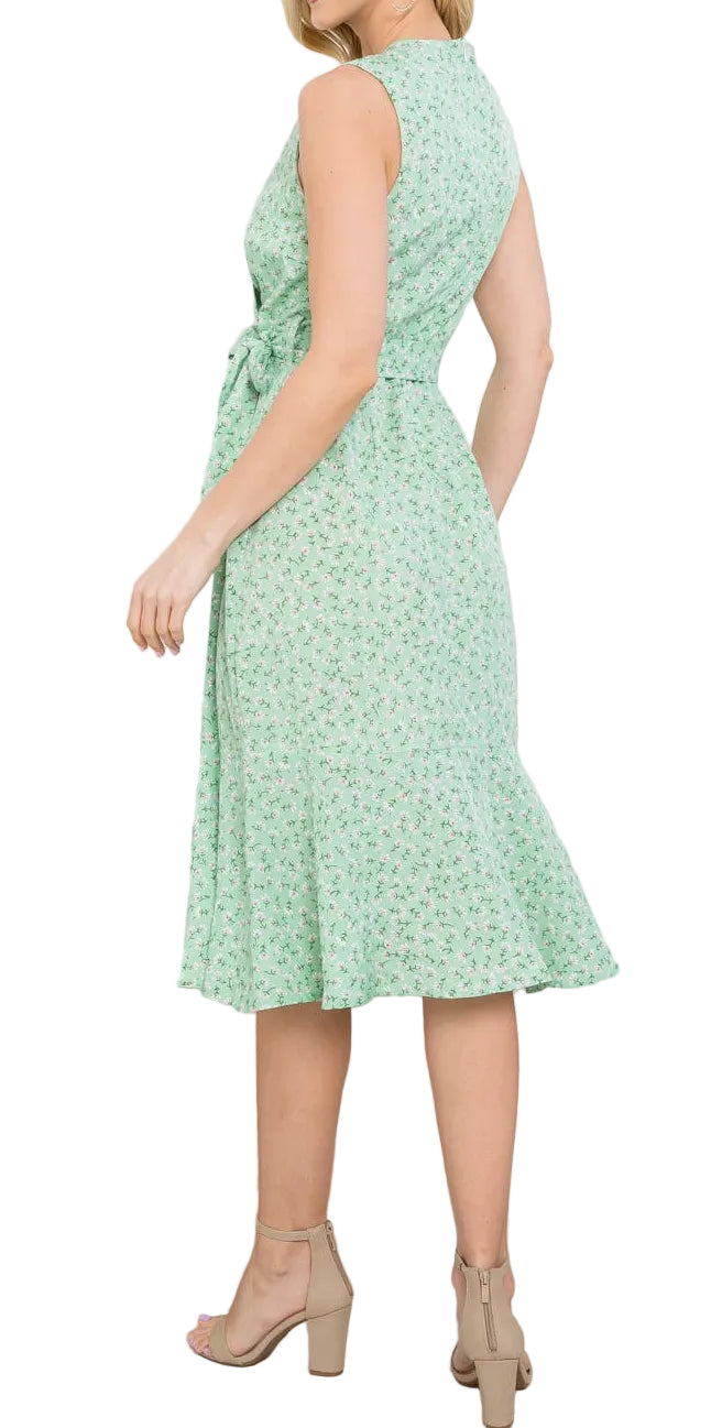 Woman wearing a light green floral dress in a home setting with plants and decor.