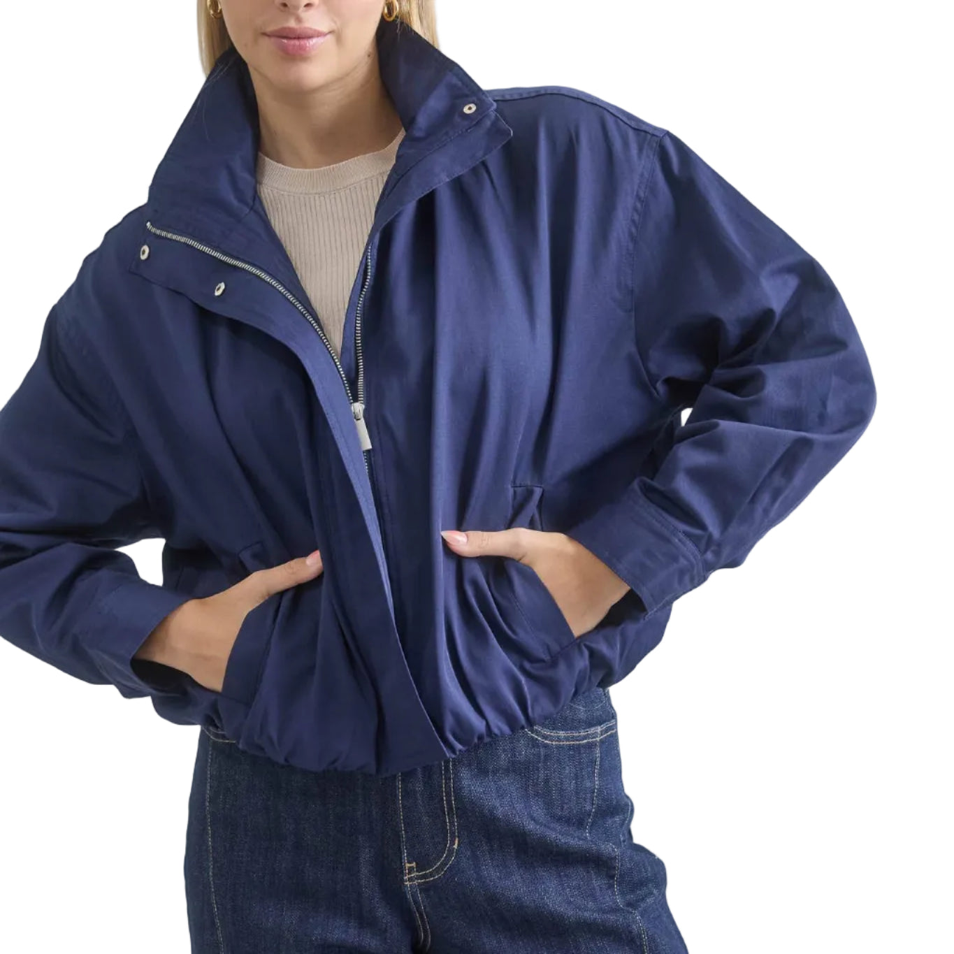 Person wearing a blue jacket and jeans on a plain background