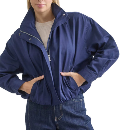 Person wearing a blue jacket and jeans on a plain background