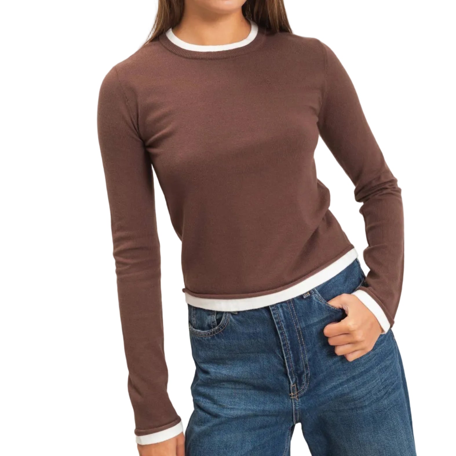 A woman modeling a fitted long-sleeve crewneck top in brown with white ribbed trim at the collar, cuffs, and hem, paired with blue jeans against a plain light background.