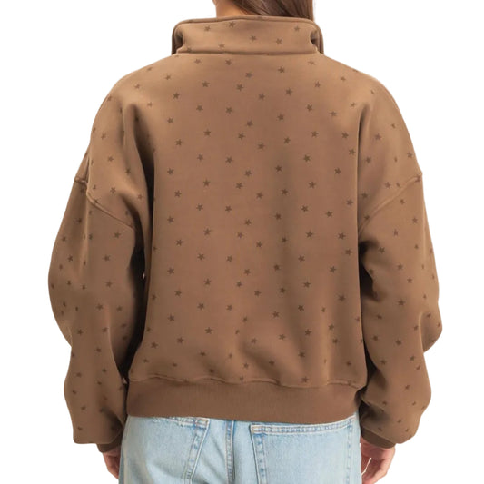 A woman viewed from behind wearing a brown cropped sweatshirt with a subtle repeating star pattern and light-wash blue jeans, set against a plain off-white background.