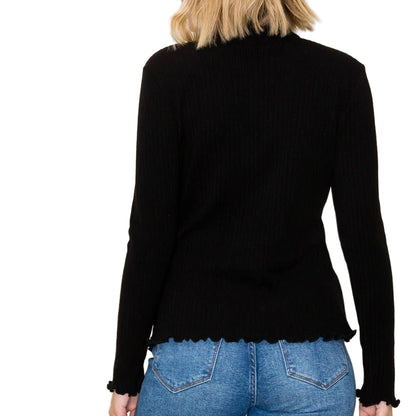 Person wearing a black long-sleeve top and blue jeans against a plain background