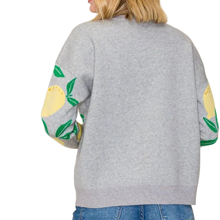 Gray sweater with colorful sleeves worn by a person on a plain background