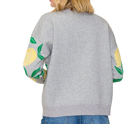 Gray sweater with colorful sleeves worn by a person on a plain background