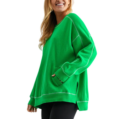 Person wearing a bright green oversized sweater with black leggings and brown boots on a white background