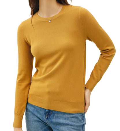 Woman wearing a mustard yellow sweater and blue jeans against a plain background