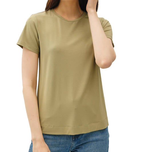 Woman wearing a green t-shirt and blue jeans against a plain background
