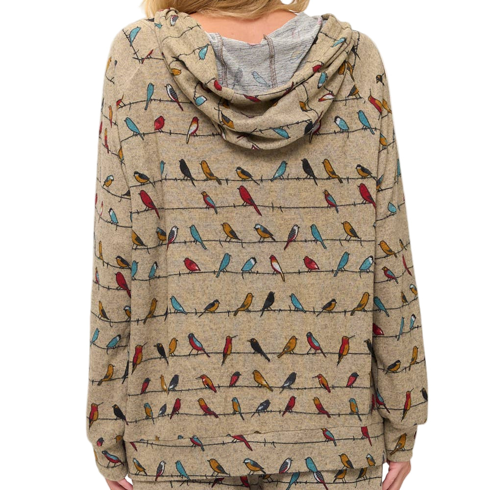 Person wearing a beige hoodie with colorful bird pattern on a white background