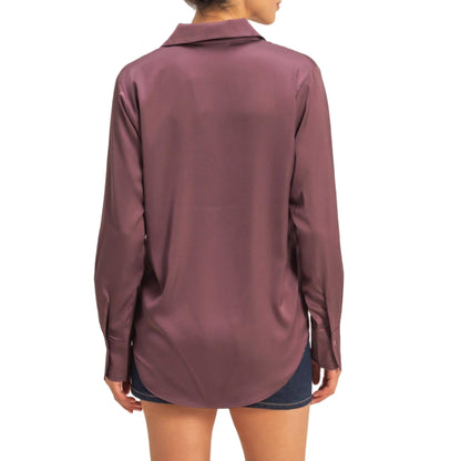 Woman wearing a long-sleeve maroon shirt against a beige background