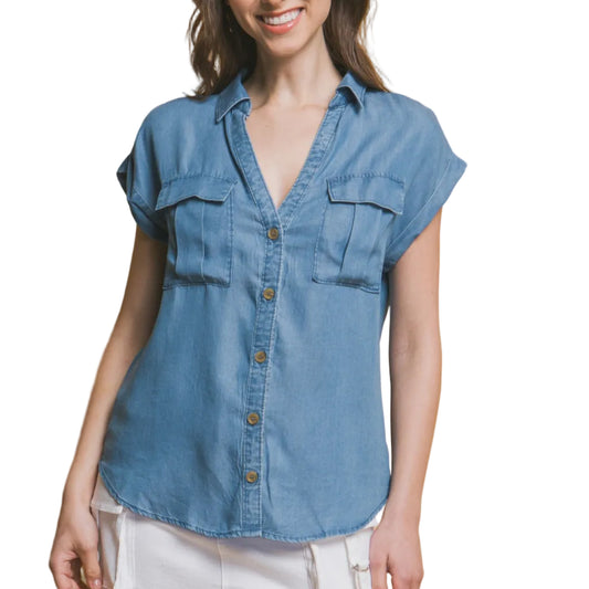 Woman wearing a blue denim top and white skirt against a beige background