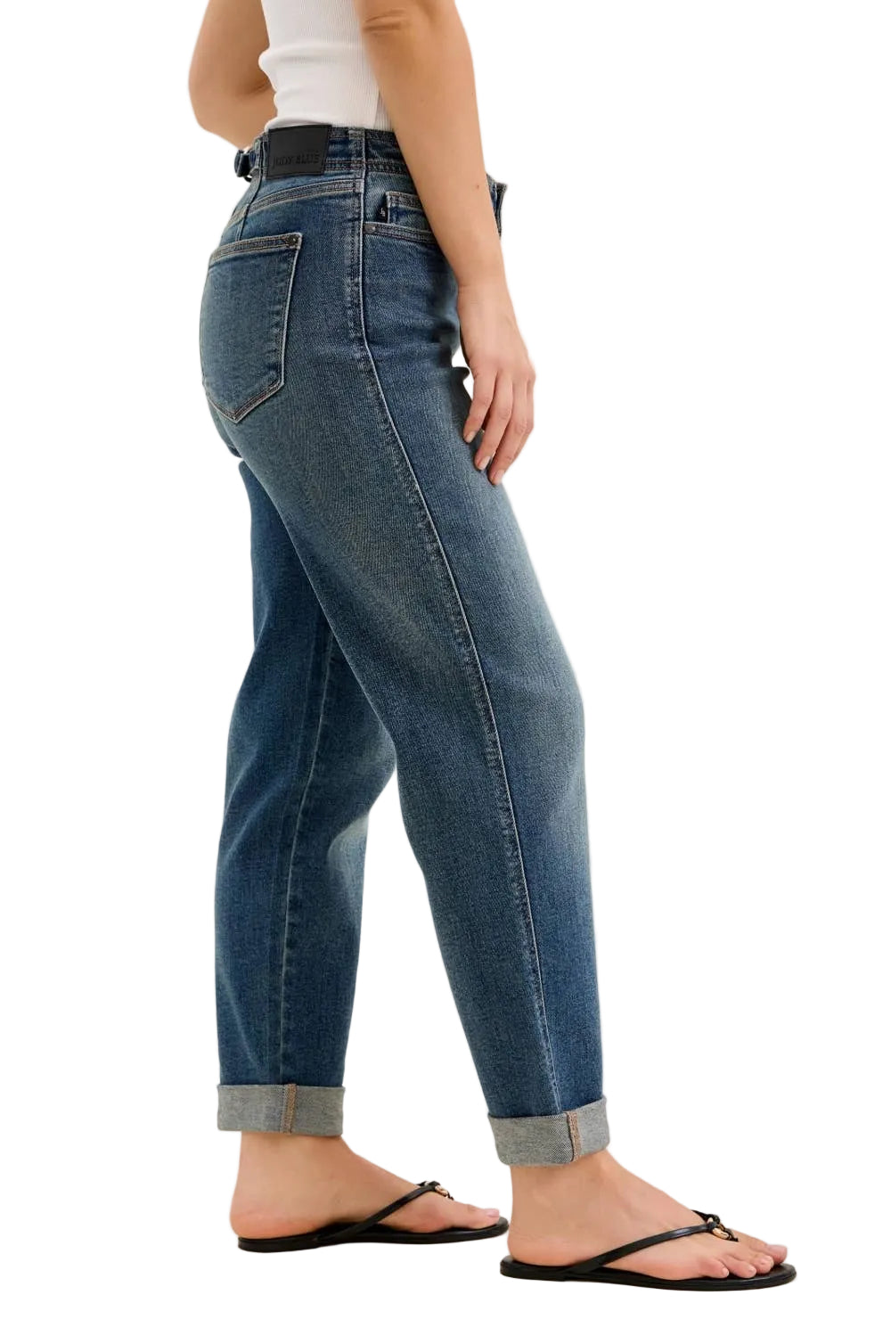 Person wearing blue jeans and a white top on a plain background