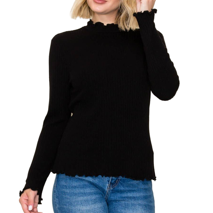 Woman wearing a black sweater and blue jeans against a plain background