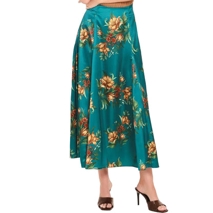 A woman modeling a sleeveless brown ribbed knit top and a teal midi skirt with a large orange and yellow floral print, paired with brown heeled sandals, against a plain light background.