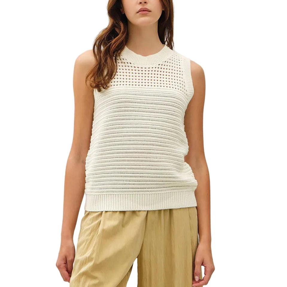 Woman wearing a white sleeveless top and beige pants on a white background