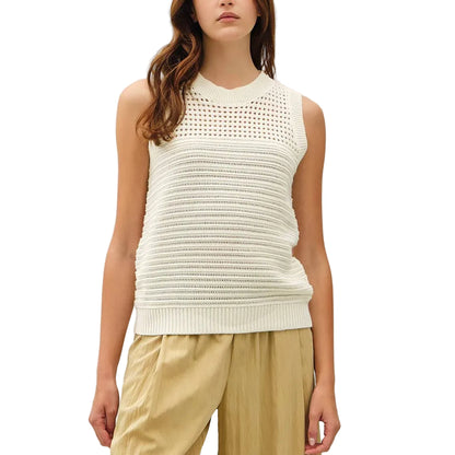 Woman wearing a white sleeveless top and beige pants on a white background