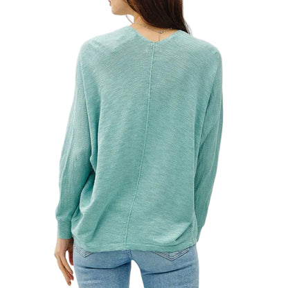 Person wearing a teal sweater and light blue jeans on a white background