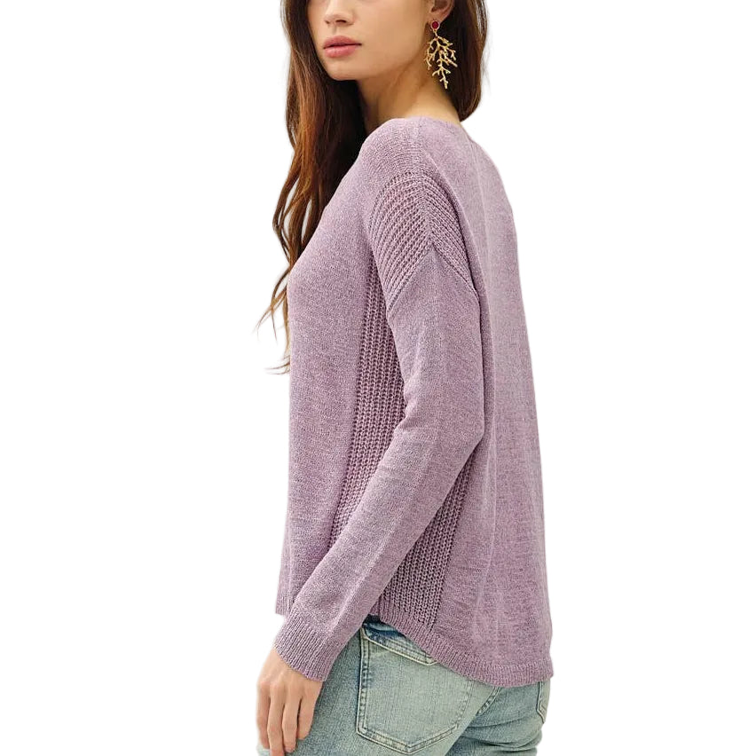 Woman wearing a purple sweater and light blue jeans on a white background