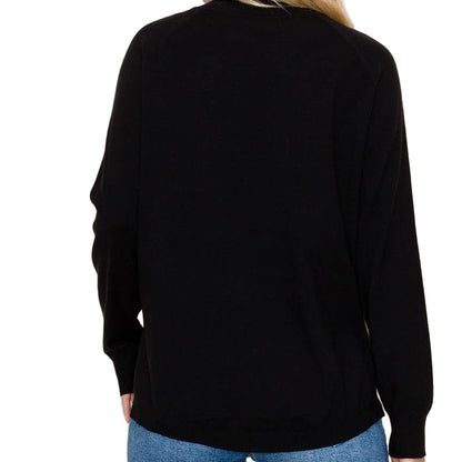 Person wearing a black long-sleeve top and blue jeans against a beige background