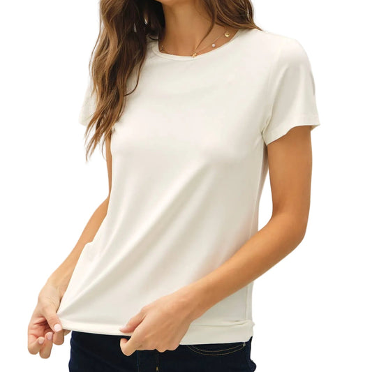 Woman wearing a white t-shirt and dark jeans against a plain background