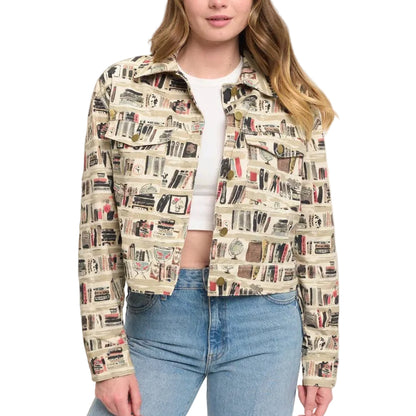 A woman modeling a cropped jacket with an all-over book spine print, styled with a white crop top and blue jeans in a minimalist indoor setting.