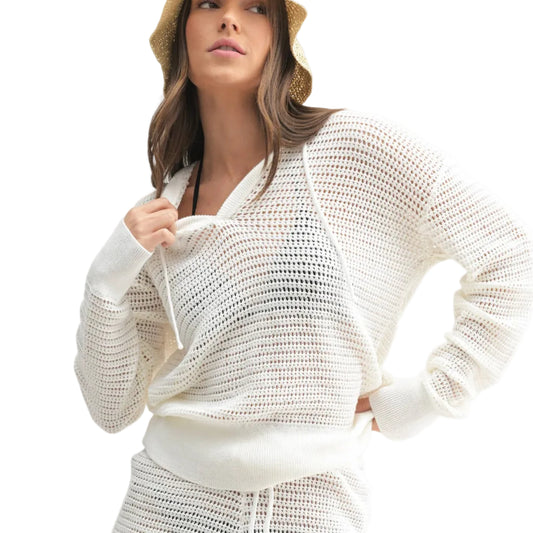 Woman wearing a white crochet outfit with a hat on a light gray background